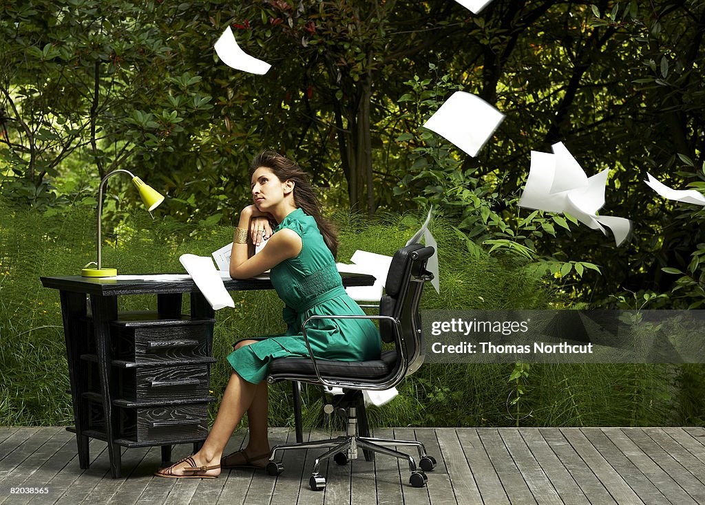 Woman sitting at desk with papers flying