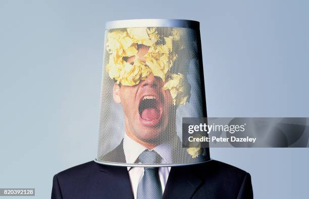 businessman with waste paper bin on head - política de escritório imagens e fotografias de stock