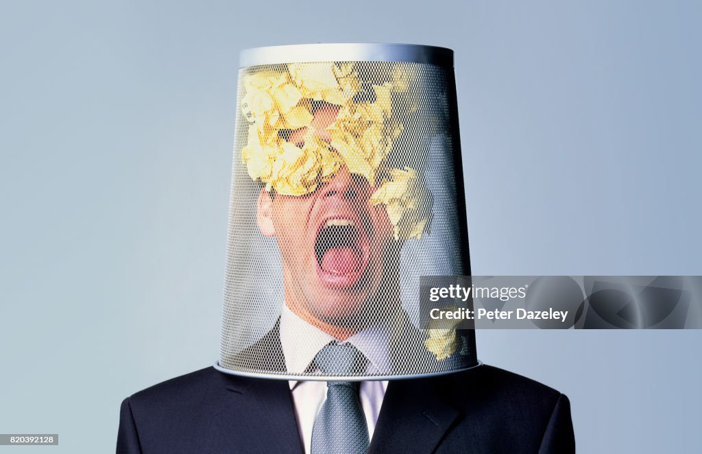 Businessman with waste paper bin on head