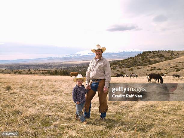 portrait of father and son on range with wild horses - montana ranch stock pictures, royalty-free photos & images