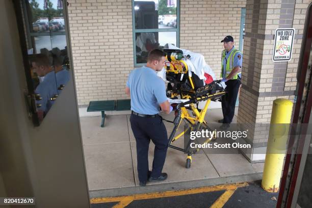 Firefighter Tyler Behrends and Brian Maschke bring an overdose victim into a hospital on July 14, 2017 in Rockford, Illinois. The woman was found on...