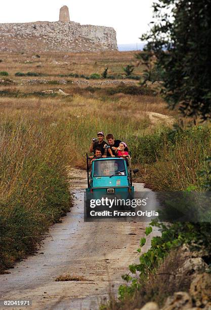 Boys run over an old Ape near Sant'Emiliano Tower in Uggiano la Chiesa on August 16 in Salento, Italy. Salento is that strip of land that forms the...