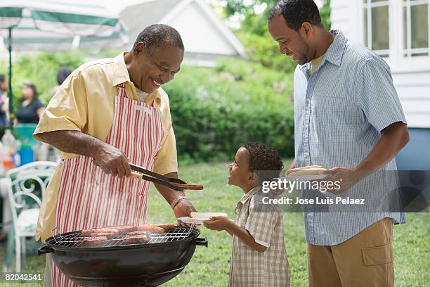 african american grandfather with grandson and son at outdoor grill - american bbq stock pictures, royalty-free photos & images