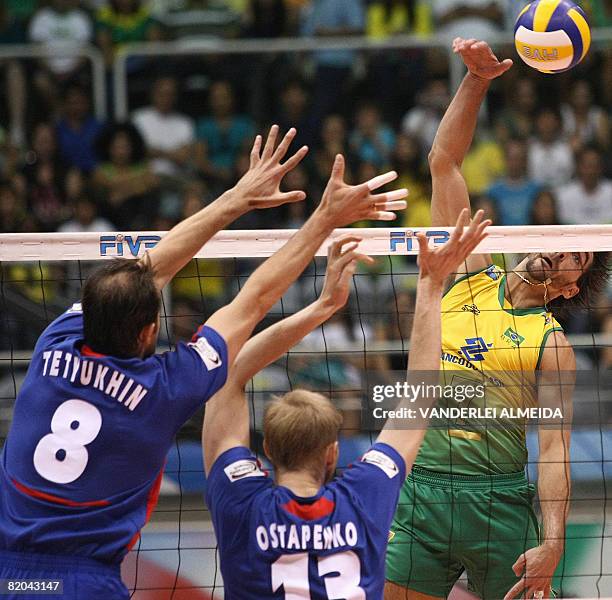 Brazil's Gilberto Godoy spikes the ball over the Russian blockade of Sergei Tetyukhin and Alexei Ostapenko during their International Volleyball...