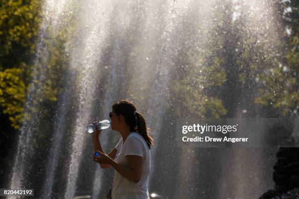 Woman sips water as he takes in the mist from Bailey Fountain at Grand Army Plaza, July 21, 2017 in the Brooklyn borough of New York City....