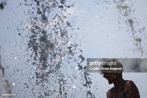 Woman cools off in a fountain in Battery Park in Lower Manhattan, July 21, 2017 in New York City. Temperatures are soaring into the 90s again on...