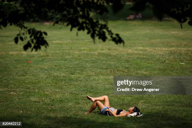 Woman sunbathes in Prospect Park, July 21, 2017 in the Brooklyn borough of New York City. Temperatures are soaring into the 90s again on Friday in...