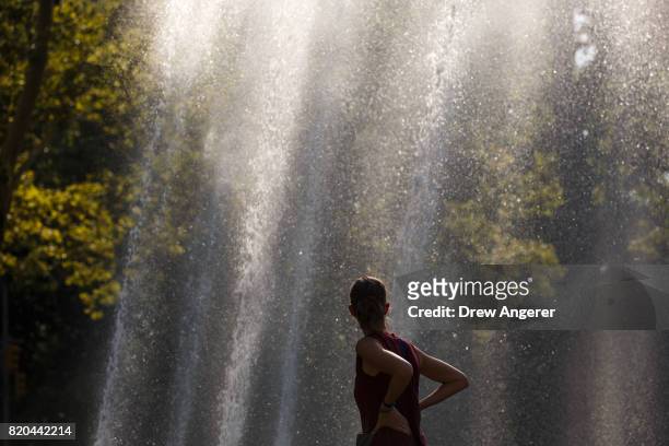 Woman takes in the mist from Bailey Fountain at Grand Army Plaza, July 21, 2017 in the Brooklyn borough of New York City. Temperatures are soaring...