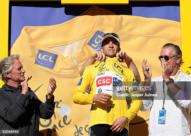 Stage winner and new race leader Carlos Sastre of Spain and team CSC Saxo Bank stands receiving the yellow jersey applauded by actor Michael Douglas...