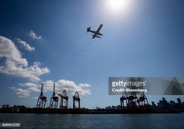 Harbour Air seaplane prepares to land on the harbour as gantry cranes stand at the Port of Vancouver in Vancouver, British Columbia, Canada, on...