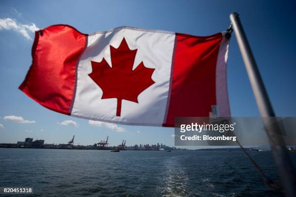 Canadian flag flies from a Harbour Authority patrol boat as gantry cranes are seen at the Port of Vancouver in Vancouver, British Columbia, Canada,...