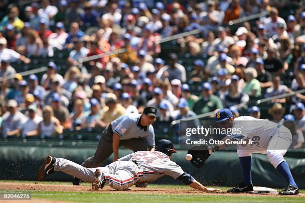 Bryan LaHair of the Seattle Mariners awaits the throw as Grady Sizemore of the Cleveland Indians dives back to first during the game on July 19, 2008...