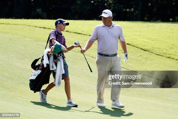 Dudley Hart of the United States hands a club to his son and caddie Ryan Hart on the fifth hole during the second round of the Barbasol Championship...