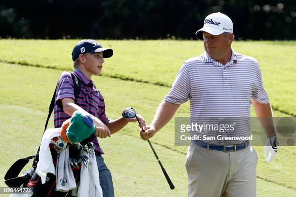 Dudley Hart of the United States hands a club to his son and caddie Ryan Hart on the fifth hole during the second round of the Barbasol Championship...