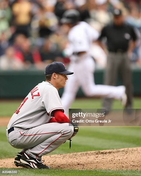 Starting pitcher Clay Buchholz of the Boston Red Sox squats down as lead runner Jose Lopez of the Seattle Mariners passes third base on a two run...