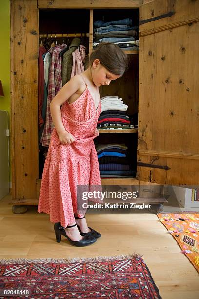 little girl trying on her mother's shoes and dress - girls shoes stock-fotos und bilder