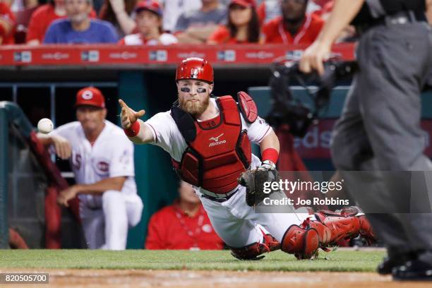 Tucker Barnhart of the Cincinnati Reds flips the ball toward the plate after a wild pitch by Homer Bailey allowed a run to score in the first inning...