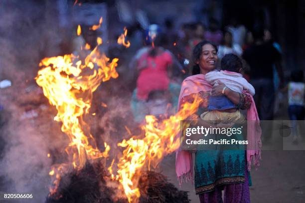 Nepalese devotee caries her child close to a burning straw effigy of the demon Ghantakarna during the Gathemangal festival celebrated at Bhaktapur,...