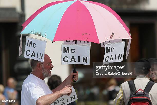 Man carries an umbrella, decorated with Mc Cain posters during the visit of Barack Obama at the Brandenburg Gate on July 24, 2008 in Berlin, Germany....