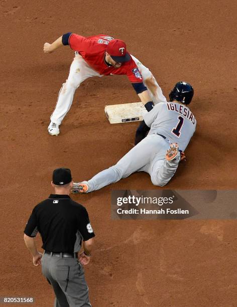 Brian Dozier of the Minnesota Twins catches Jose Iglesias of the Detroit Tigers stealing second base as umpire Will Little looks on during the fourth...