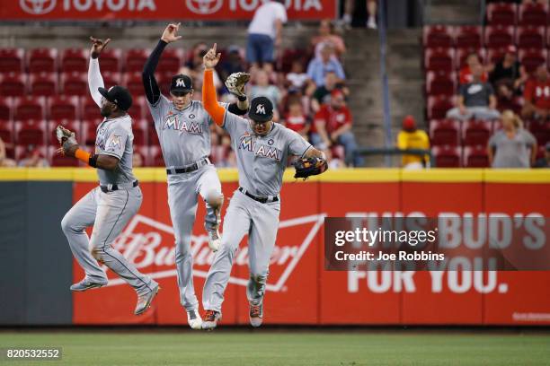 Marcell Ozuna, Christian Yelich and Giancarlo Stanton of the Miami Marlins celebrate after the final out of the game against the Cincinnati Reds at...