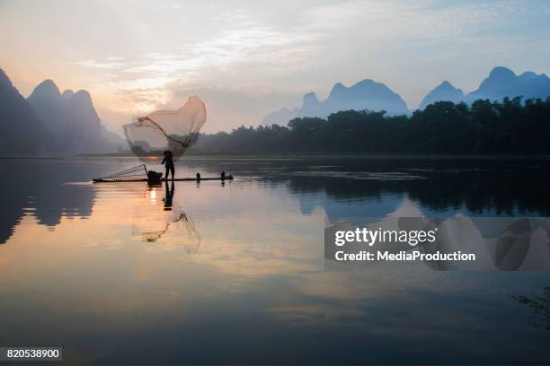 chinese fisherman fishing with a throw net on river li near guilin - net fishing stock pictures, royalty-free photos & images