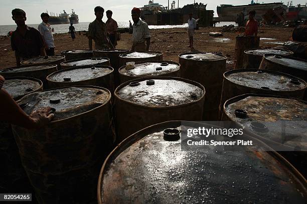 Ship breakers move barrels of oil to shore from a ship that is being dismantled for scrap July 24, 2008 in the port city of Chittagong, Bangladesh....