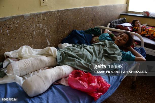 In this photograph taken on July 21 Afghan girl Shazia looks at her injuries after losing her lower legs in an explosion after stepping on a landmine...