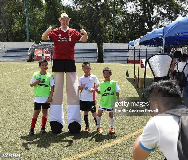Children pose for a photograph with a man on stilts during a soccer school on July 22, 2017 in Hong Kong, Hong Kong.