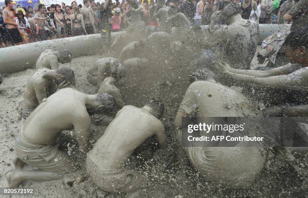 Tourists play with mud in a mud pool during the 20th Boryeong Mud Festival at Daecheon beach in Boryeong on July 22, 2017. The annual festival which...