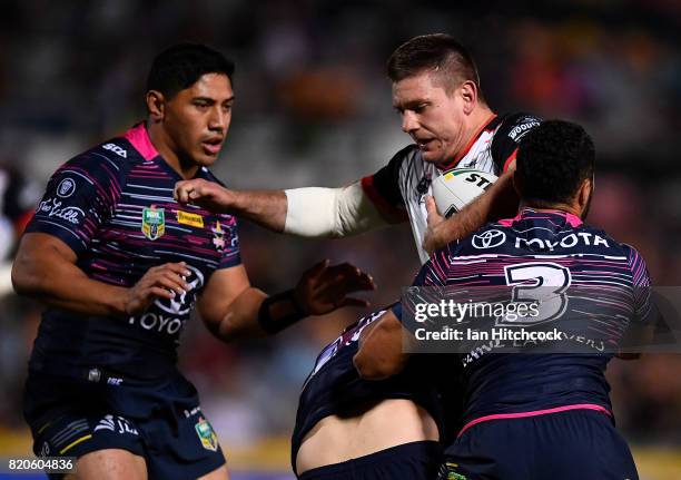 Jacob Lillyman of the Warriors is tackled by Justin O'Neil and Jason Taumalolo of the Cowboys during the round 20 NRL match between the North...