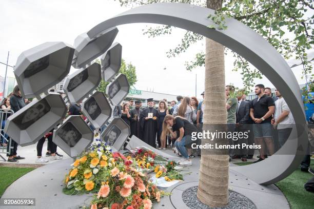 Mourners lie down flowers at a memorial during an event to commemorate the first anniversary of the shooting spree that one year ago left ten people...
