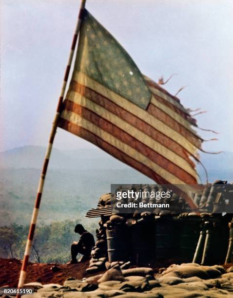 Tattered American flag flies above firebase LZ Lonely, and is typical of fortified positions used to support ground forces with artillery. A bullet...