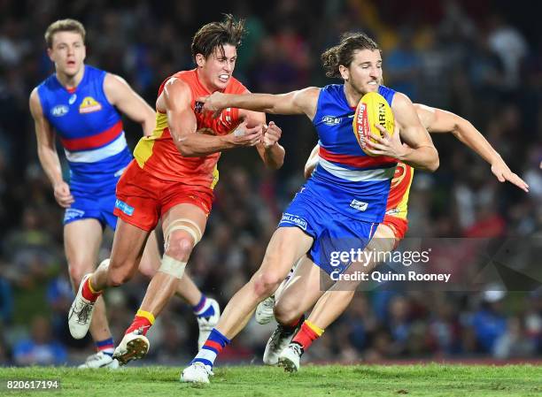 Marcus Bontempelli of the Bulldogs fends off a tackle by David Swallow of the Suns during the round 18 AFL match between the Western Bulldogs and the...