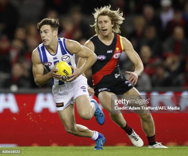 Declan Mountford of the Kangaroos in action ahead of Dyson Heppell of the Bombers during the 2017 AFL round 18 match between the Essendon Bombers and...