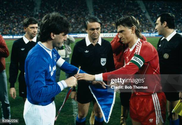 Bayern Munich captain Klaus Augenthaler and Everton's Kevin Ratcliffe exchange pennants under the watchful eye of the match officials prior to their...