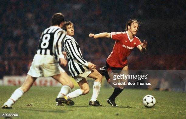 Manchester United's Arthur Graham moves past Juventus' Michel Platini as Marco Tardelli moves in, during their European Cup Winners Cup Semi-Final...