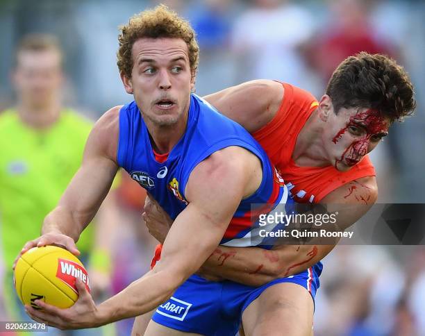Mitch Wallis of the Bulldogs is tackled by Sean Lemmens of the Suns during the round 18 AFL match between the Western Bulldogs and the Gold Coast...