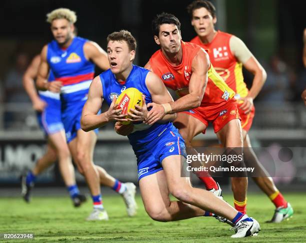 Jackson Macrae of the Bulldogs is tackled by Matt Rosa of the Suns during the round 18 AFL match between the Western Bulldogs and the Gold Coast Suns...