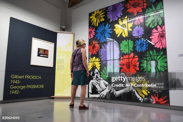 Woman stands in front of an artwork named "Flower worship" by Gilbert and George during an exhibition named 'Histoires d'ateliers' on July 22 at the...