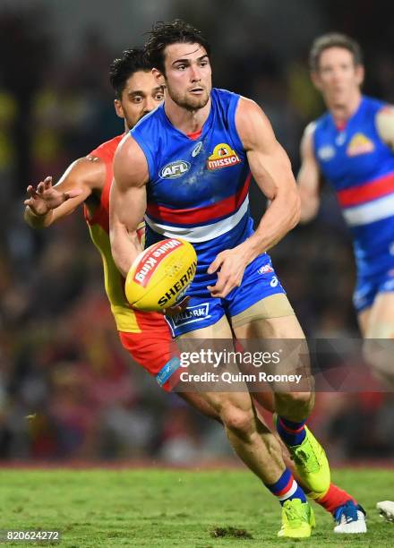 Easton Wood of the Bulldogs handballs whilst being tackled by Aaron Hall of the Suns during the round 18 AFL match between the Western Bulldogs and...