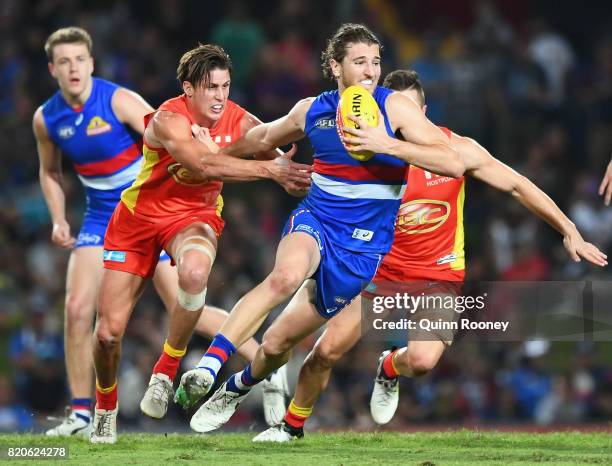 Marcus Bontempelli of the Bulldogs fends off a tackle by David Swallow of the Suns during the round 18 AFL match between the Western Bulldogs and the...