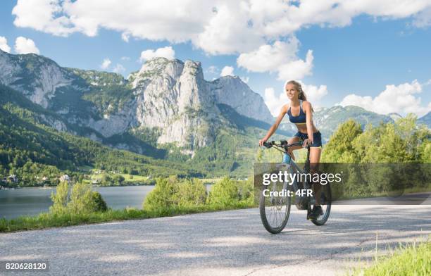 woman riding on her e-bike mountainbike, lake grundlsee, austria - e sport stock pictures, royalty-free photos & images