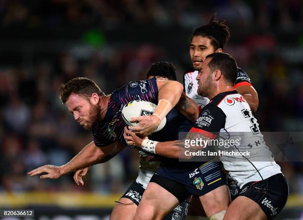 Gavin Cooper of the Cowboys is tackled by Bodene Thompson and Issac Luke of the Warriors during the round 20 NRL match between the North Queensland...