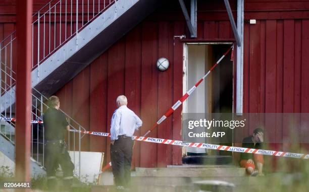 Two police officers view a woman crying outside a building after clashes with asylum seekers at Valer 45 kilometres, southeast of Oslo on July 25,...