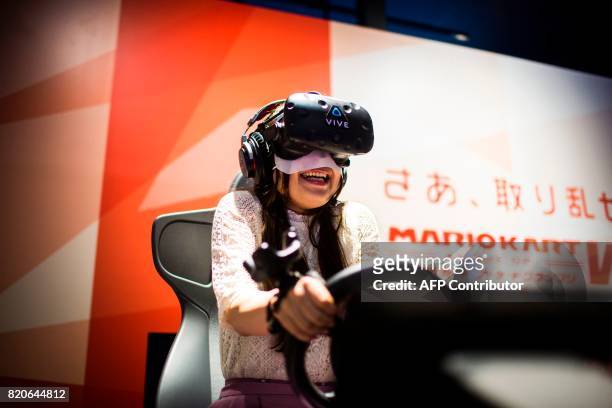 Woman plays a virtual reality Mario Kart game at the Bandai Namco game facility of VR Zone Shinjuku in Tokyo on July 22, 2017. / AFP PHOTO / Behrouz...