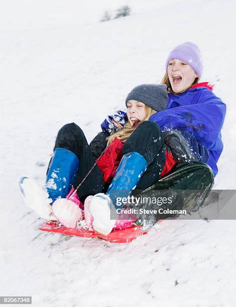 two teenage girls, 13 years and 14 years old, sliding down hill on sledge - 12 13 14 15 years girl stock pictures, royalty-free photos & images