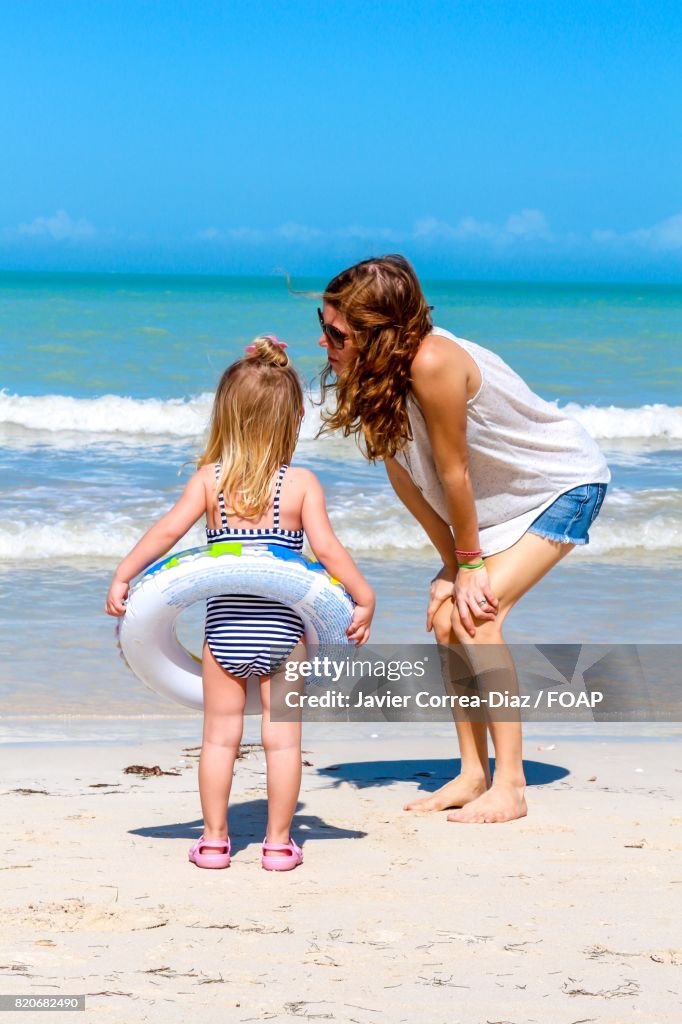 Child and mom standing on beach