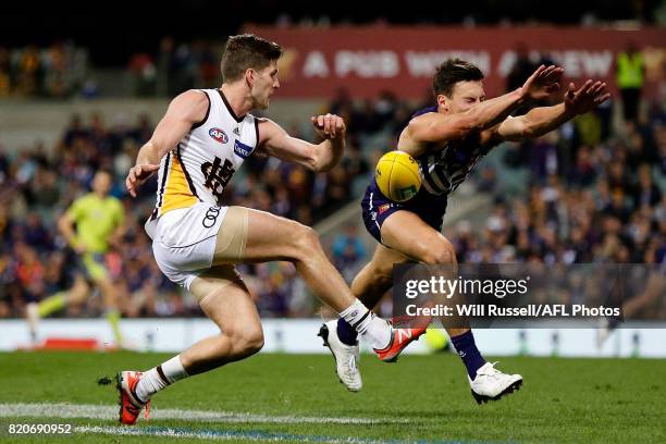 Ethan Hughes of the Dockers tries to spoil a kick from Luke Breust of the Hawks during the round 18 AFL match between the Fremantle Dockers and the...