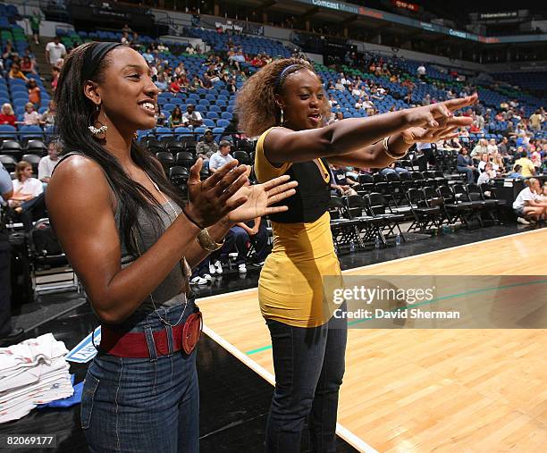 Though currently on the injured list, Candice Wiggins and Charde Houston of the Minnesota Lynx cheer on their team during warm-ups prior to the game...